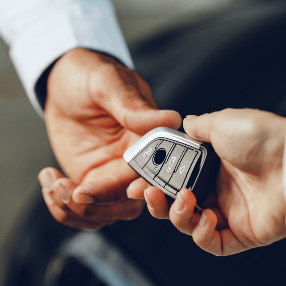 Car salesperson giving keys to a client close up