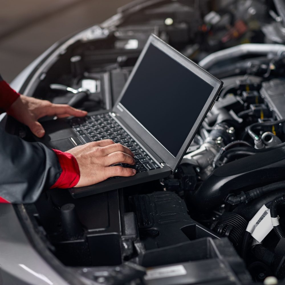 Crop mechanic conducting car diagnostics in workshop