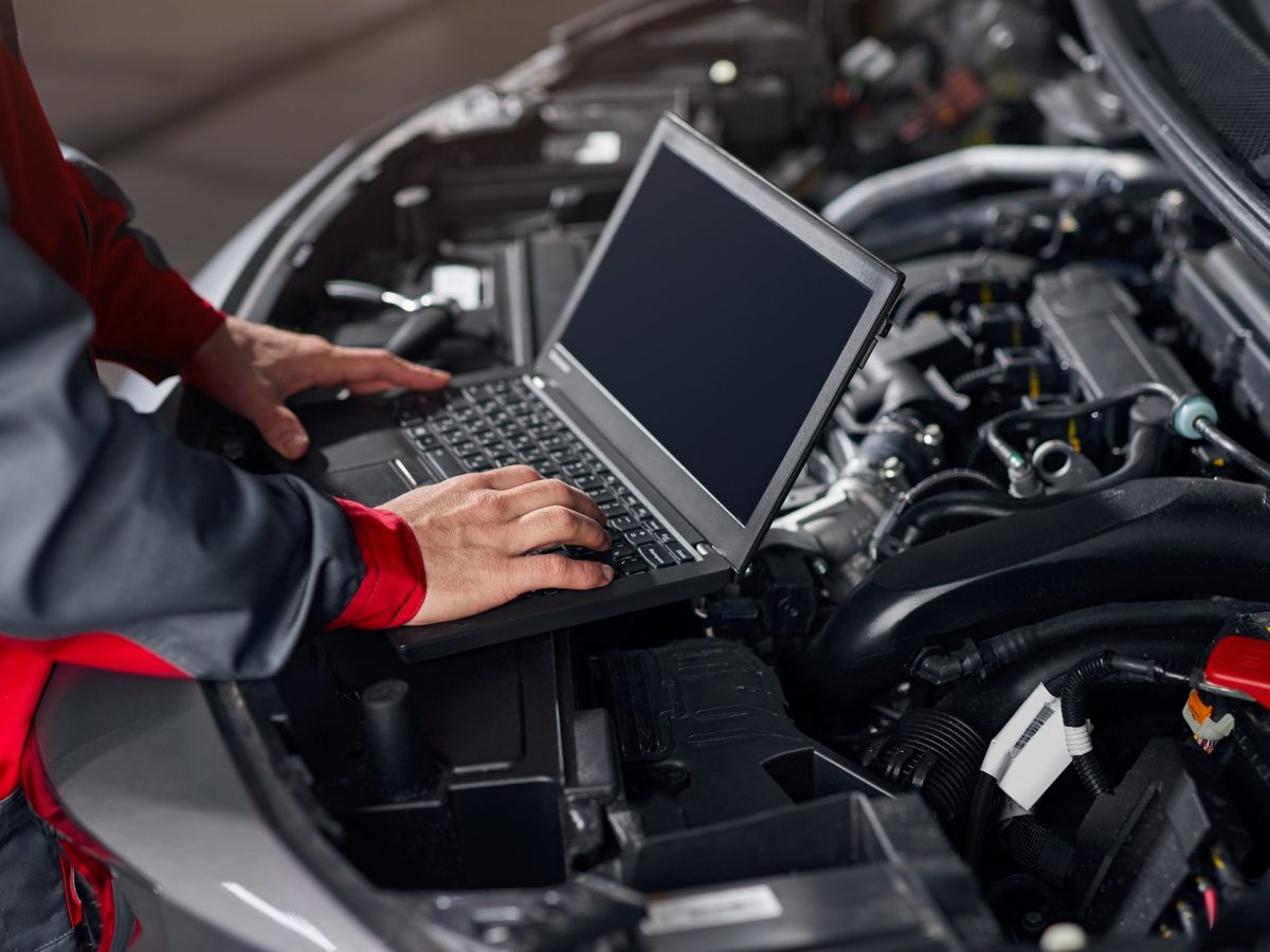 Crop mechanic conducting car diagnostics in workshop